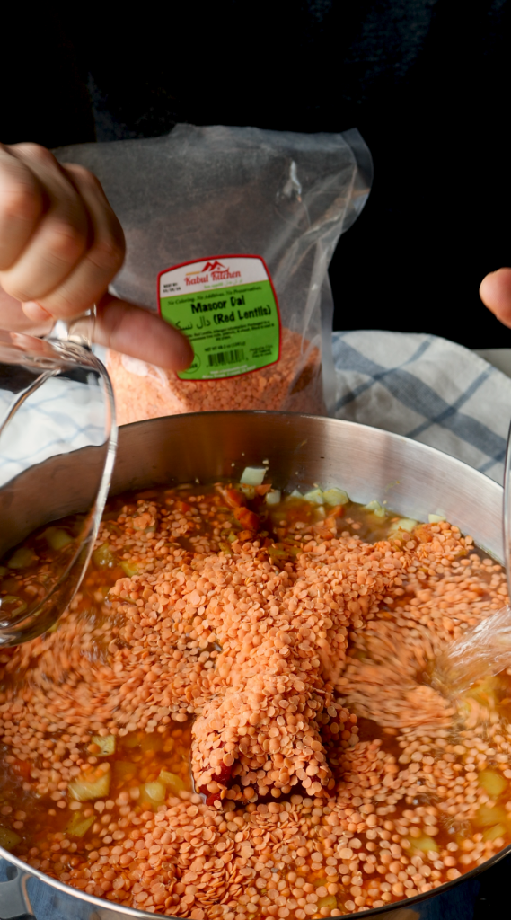 To make this creamy red lentil soup, begin by sautéing onions and minced garlic in oil. Then add carrots and seasonings. Cook for a few minutes, then add tomato paste, red lentils, and water. Bring to a boil, then cover and cook on super low for 30 minutes, or until lentils and carrots are soft. Blend until smooth, then add heavy cream. Add more heavy cream if a more soupy consistency is desired. Top with red pepper flakes and cilantro and enjoy!